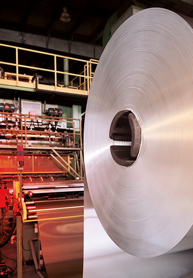 Aluminum coil progressing through a production line in an aluminum manufacturing facility.